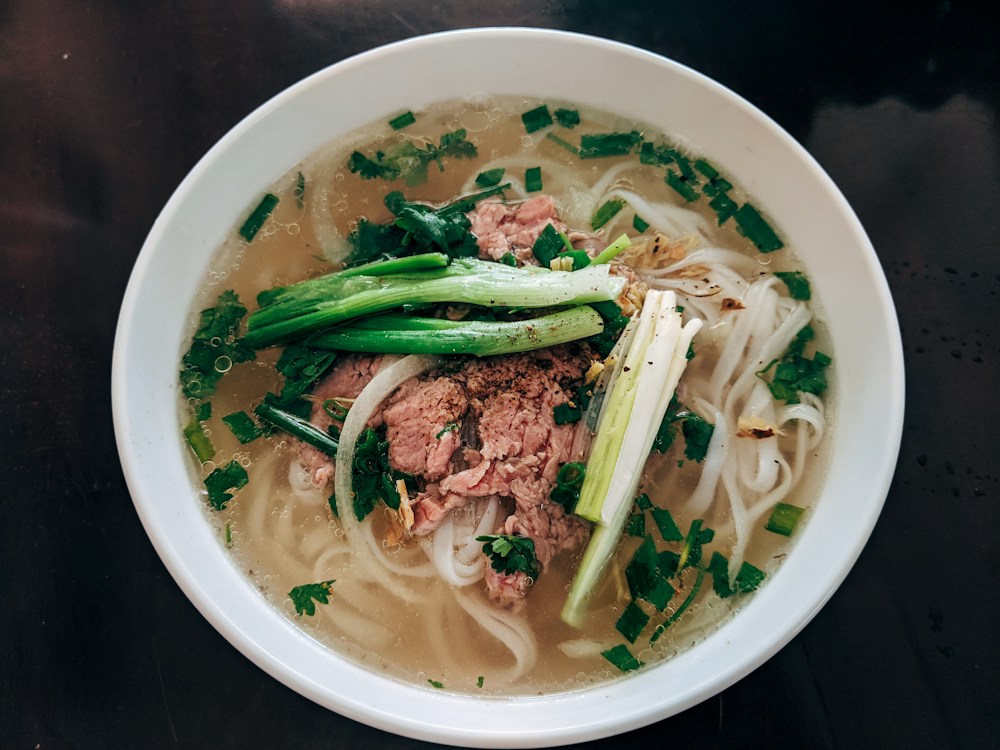 Bowl of beef phở with scallions and herbs